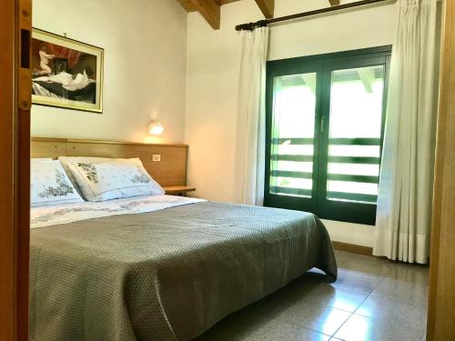 a bedroom with a bed and a large window at Casa Felicita in Ledro