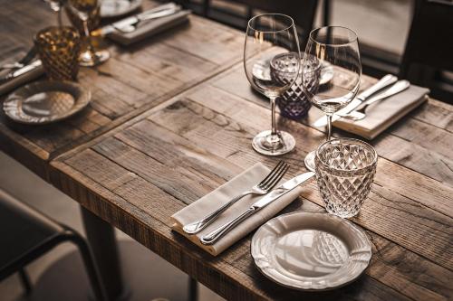 a wooden table with plates and wine glasses on it at Locanda Cossetti Ranch Winery in Incisa Scapaccino
