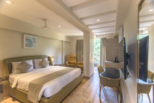 a bedroom with a bed and a desk and chairs at The Fern Residency Calangute-Baga, Goa in Calangute