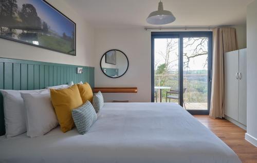 una camera da letto con un grande letto bianco con cuscini gialli di The Mole Resort - Lodges a Chittlehamholt