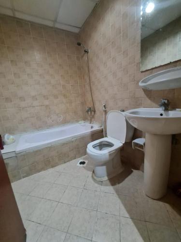 a bathroom with a toilet and a sink and a tub at Almond Tower, Garden City in Ajman 