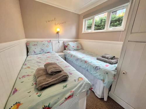 a small room with two beds and two windows at Shrimpy- A cute family friendly chalet in Cromer in Cromer