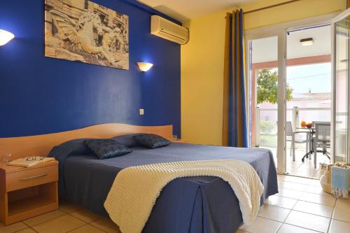 1 dormitorio con 1 cama con pared azul en Résidence Villa Romana avec spa, en Propriano