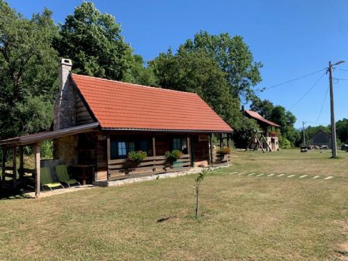 a log cabin with an orange roof in a field at Holiday Home Anka in Gospić