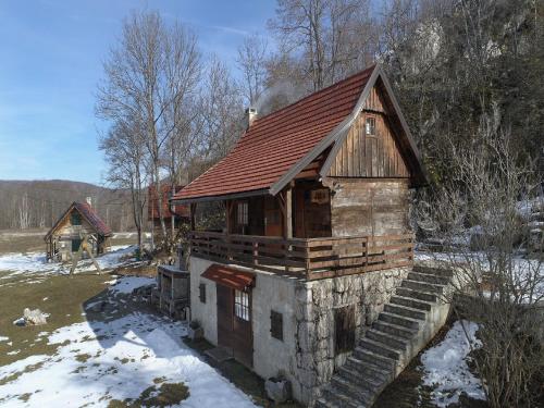 an old log cabin with snow on the ground at Holiday Home Jela in Gospić