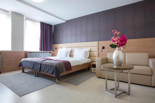 a bedroom with a bed and a vase of flowers on a table at Hotel Srbija Garden-FREE PARKING in Belgrade