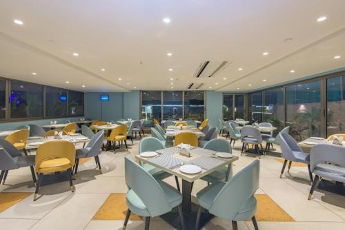 a restaurant with tables and chairs and windows at The Fern Residency Calangute-Baga, Goa in Calangute