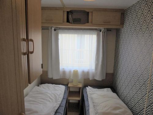 two beds in a small room with a window at 8 Berth on The Chase Ingoldmells Nordstar in Skegness