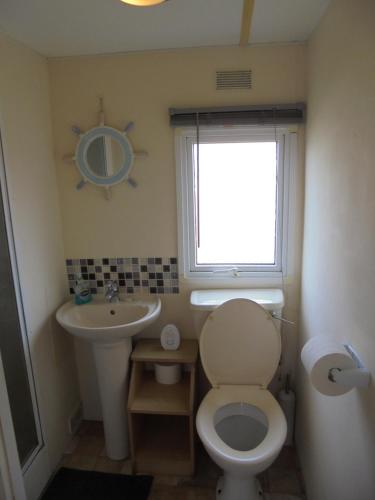 a bathroom with a toilet and a sink and a window at 8 Berth on The Chase Ingoldmells Nordstar in Skegness