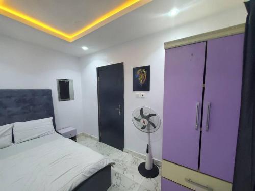 een slaapkamer met een bed en een paarse kast bij Spacious 2-bed Apt With 24hrs Power+ Unlimited Wi-Fi in Lagos