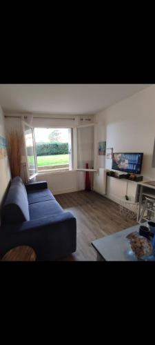 un salon avec un canapé bleu et une grande fenêtre dans l'établissement Studio - Phalènes proche CID, à Deauville