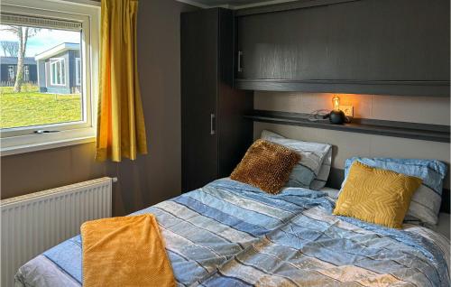 een slaapkamer met een bed met gele kussens en een raam bij Nice Home In Scherpenisse With Kitchen in Scherpenisse