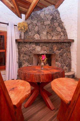 a stone fireplace with a wooden table and two benches at Pousada Alpes da Mantiqueira in Monte Verde