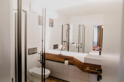 uma casa de banho com um lavatório, um WC e um espelho. em Peak Hotel & Event em Salzgitter