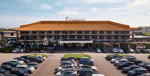 un edificio con muchos coches aparcados en un estacionamiento en Van der Valk Hotel Breukelen, en Breukelen