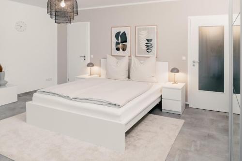 a white bedroom with a white bed and two lamps at Soulplace Studioapartment Gelsenkirchen in Gelsenkirchen