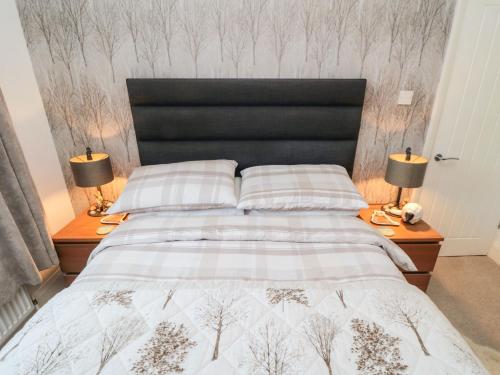 a bedroom with a bed with a black headboard and two lamps at Seaside House in Scarborough