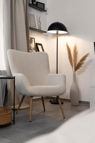 a living room with a white chair and a vase at Soulplace Studioapartment Gelsenkirchen in Gelsenkirchen