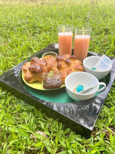 a tray with a plate of pastries and two glasses of juice at Charmant bungalow avec piscine in Saint-Joseph