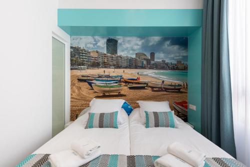 Petit Accommodation Las Canteras Deuxième في لاس بالماس دي غران كاناريا: غرفة نوم مع لوحة على الشاطئ