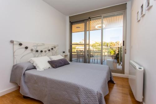 a bedroom with a bed and a large window at Cullera Beach Apartment Cap Blanc in Cullera