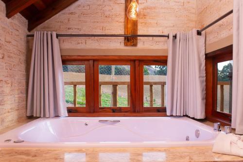 a large bath tub in a room with a window at Pousada Alpes da Mantiqueira in Monte Verde