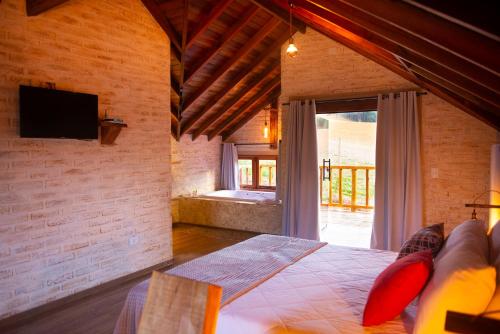 um quarto com uma cama e uma grande janela em Pousada Alpes da Mantiqueira em Monte Verde