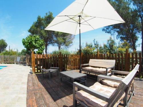 une terrasse avec une table, des bancs et un parasol dans l'établissement Villa Can Xum by Hello Homes Sitges, à Canyelles