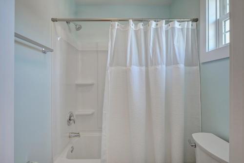 a white bathroom with a shower curtain and a tub at Loggerhead Inn and Suites in Surf City