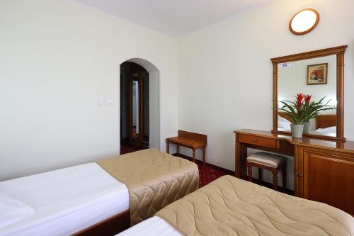 a bedroom with two beds and a dresser and a mirror at Hotel Moldova in Iaşi