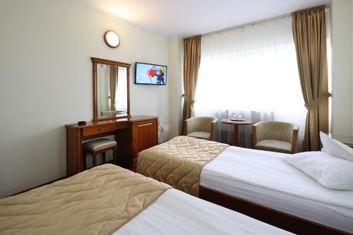 a hotel room with two beds and a mirror at Hotel Moldova in Iaşi