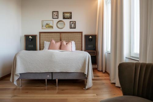 a bedroom with a bed with pink pillows on it at Fritiden Hotell & Kongress in Ystad