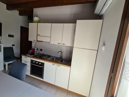 una cucina con armadi bianchi e lavandino di Appartamento in residence vicino al centro con piscina a Peschiera del Garda