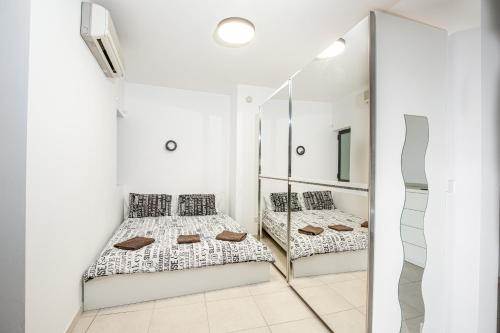 two beds in a white room with a mirror at Modern studio apartment in the heart of St Julians in St. Julianʼs