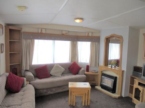 a living room with a couch and a fireplace at 6 Berth 3 bedroom panel heated on Kingfisher Florida in Ingoldmells