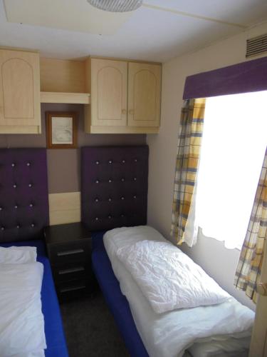 a small bedroom with two beds and a window at 8 Berth panel heated on Kingfisher Florida in Ingoldmells
