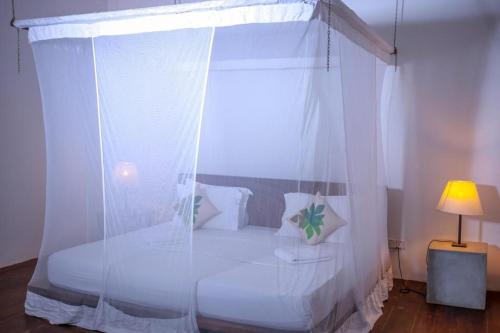 a bedroom with a canopy bed with white curtains at Knight Inn - Galle Fort in Galle