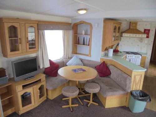 a living room with a couch and a table and a kitchen at 6 Berth 3 bedroom panel heated on Kingfisher Florida in Ingoldmells