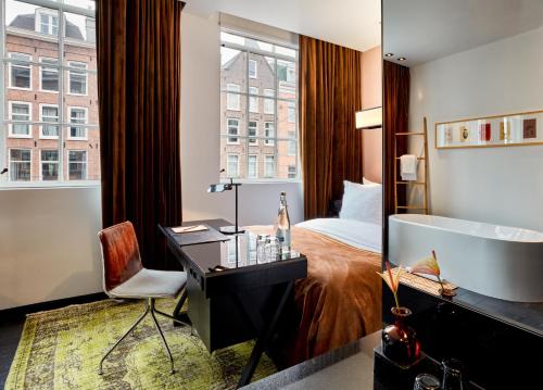 una camera d'albergo con letto, scrivania e vasca di Sir Albert Hotel, part of Sircle Collection ad Amsterdam