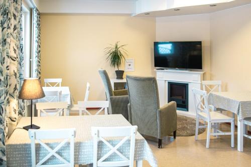 a living room with tables and chairs and a television at Hotelli Sointula in Orivesi