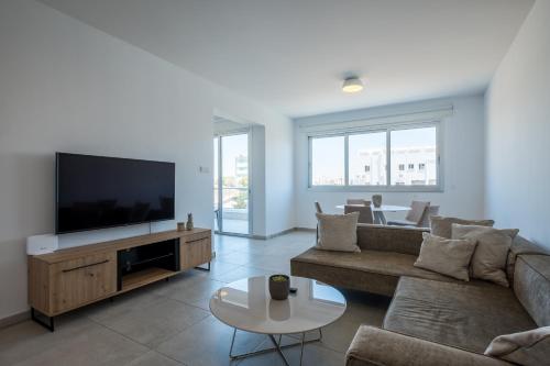 a living room with a couch and a flat screen tv at Solaar Apartments Faneromeni in Larnaka