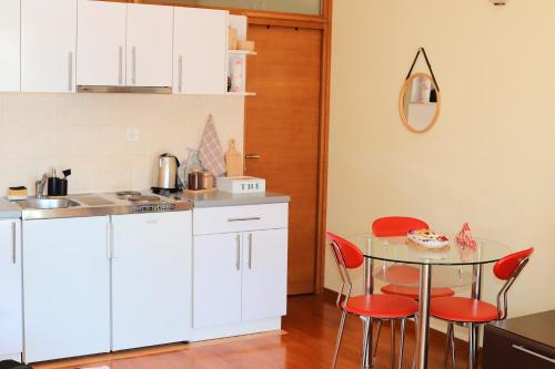 a kitchen with a glass table and red chairs at Lemon Hill in Herceg-Novi