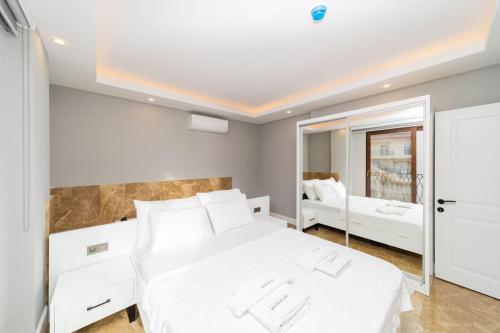 a bedroom with a white bed and a mirror at Sea View Flat with Hot Tub in Antalya Kas in Kas