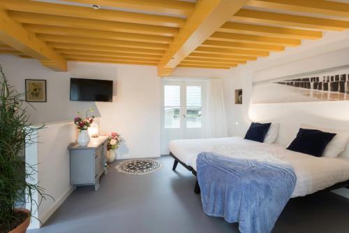 two beds in a room with white walls and a wooden ceiling at Hotel Zilt Studio's in Vlissingen