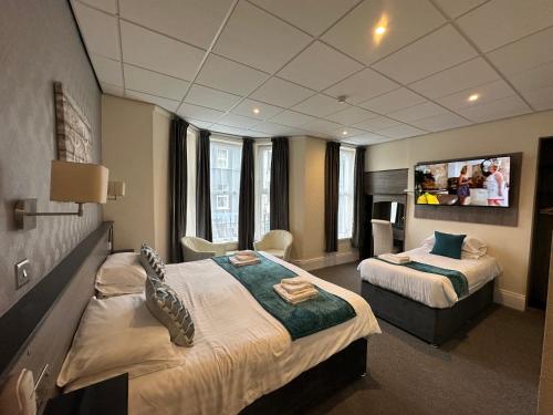 a hotel room with two beds and a flat screen tv at The Port Hotel in Portrush