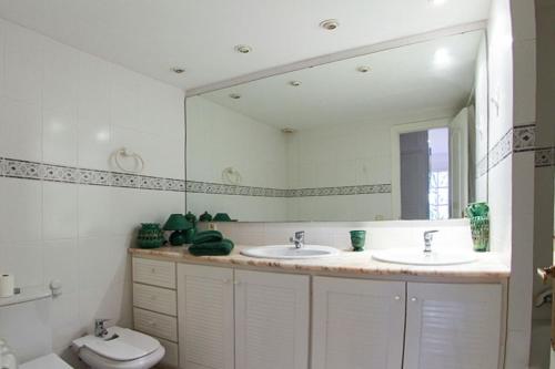 a bathroom with two sinks and a mirror and a toilet at Club Villamar - El Far in Llafranc