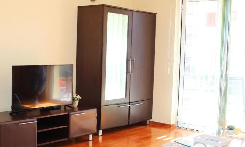 een woonkamer met een tv en een bruine kast bij Lemon Hill in Herceg-Novi