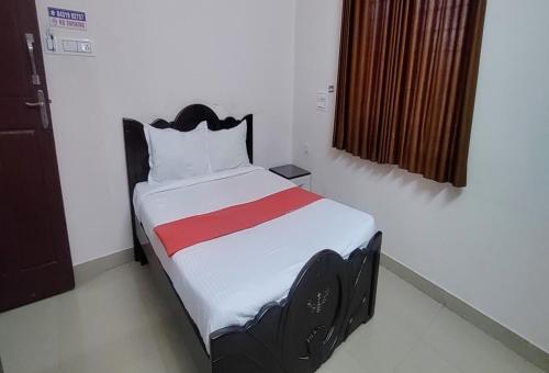 a bedroom with a bed with a red stripe on it at STAYMAKER Anjaneya Comforts in Shimoga