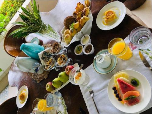 ein Tisch mit Tellern voller Essen und Gläsern mit Orangensaft in der Unterkunft Casa Brasileira - Hotel Galeria in Pôrto de Pedras