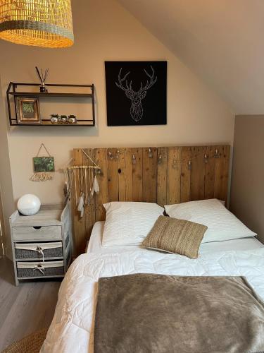 Schlafzimmer mit einem Bett mit einem Kopfteil aus Holz in der Unterkunft La Maison de Fanny in Vineuil